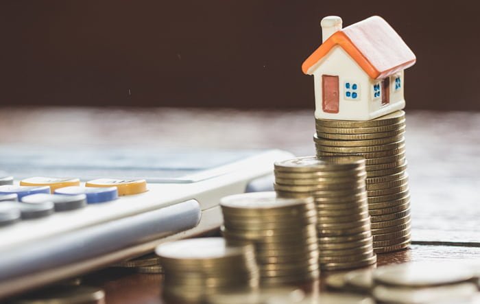 Una casa subre unas monedas reflejando la tasa de interés de las hipotecas